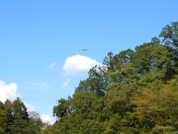 空高く飛んでいるドローンを下から写した写真
