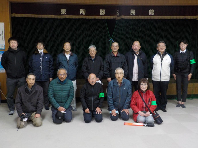 公民館の舞台の前で記念撮影をしている東陶器校区自治連合会13名の写真