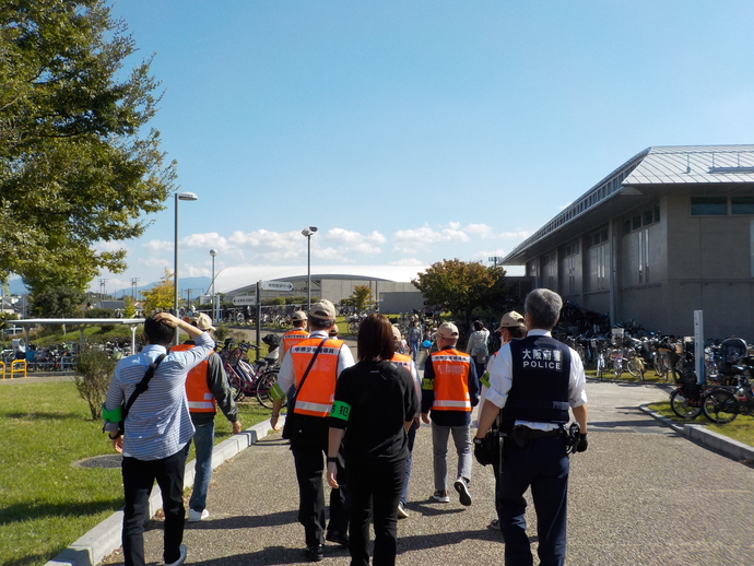 自転車がたくさん置かれた公園内をパトロールしている様子を後ろから撮影した写真