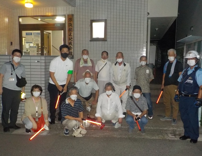 深阪校区地域会館の前で、深阪校区自治連合会の方々と男性の警察官が前列はしゃがみ、後列は立っている集合写真