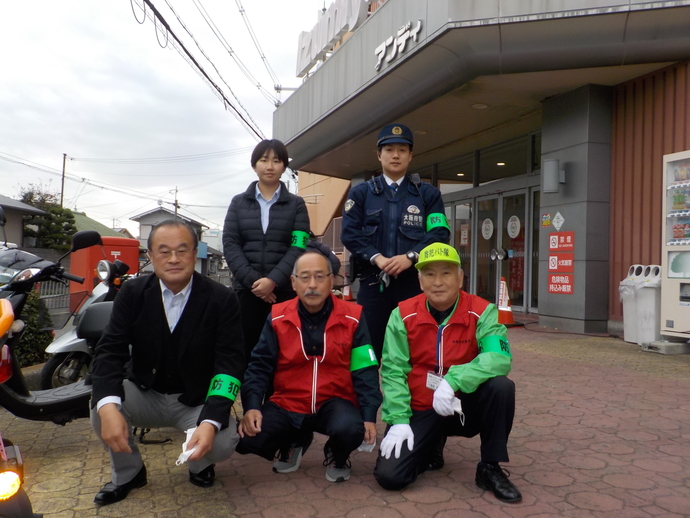 アンディの店舗前で防犯の緑のワッペンをつけた5名の方々が記念撮影をしている写真
