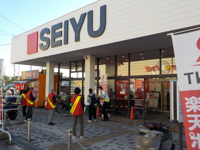 西友堺福田店の前で、赤いベストを着た方々と緑の腕章を付けた関係者の方々が防犯キャンペーンを行っている写真