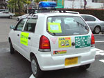 青色回転灯を装備した白い軽自動車の後ろに安全パトロール熊取町などのスッテカーを貼った写真