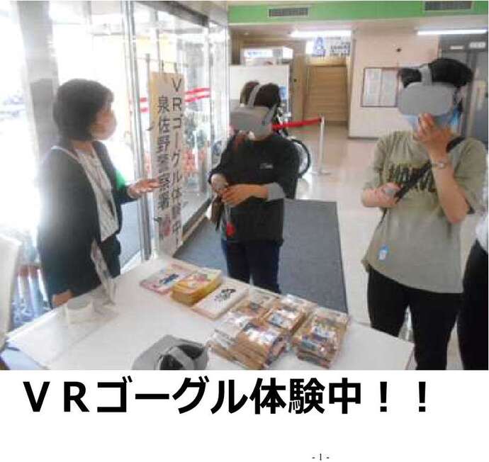 VRゴーグル体験中!!の文字と、VRゴーグルを付けた2名とスタッフが話している写真