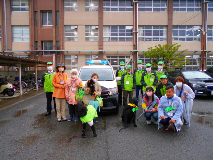小学校にて防犯パトロールカー、愛犬パトロール隊(わんだふるくらぶ)、青色防犯パトロール隊(KSP隊)が集まって撮影した集合写真