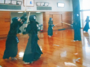 室内で剣道着姿の人たちが竹刀で打ち合っている写真