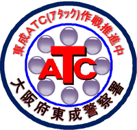 赤太字でアルファベットの「ATC」と書かれ紫色の丸が8個文字を囲むように配置され、その周りを青色と紺色の2つの丸が描かれ、その丸と丸の間に「東成ATC(アタック)作戦推進中」と「大阪府東成警察署」と書かれいている「ATC」のシンボルマークのイラスト