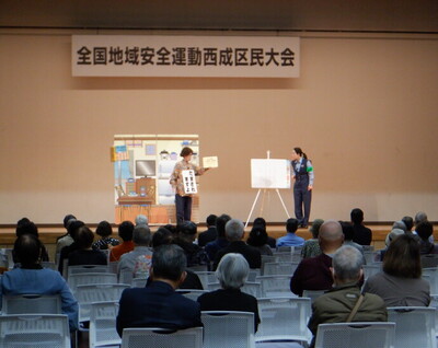舞台上で大阪府警察本部生活安全指導班の2名が行っている防犯教室の様子を会場後方から撮影した写真