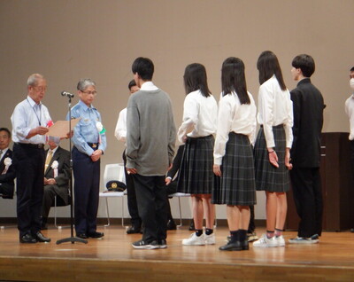 舞台上で警察署員より感謝状の表彰を受けている今宮工科高等学校の学生さん5名の写真