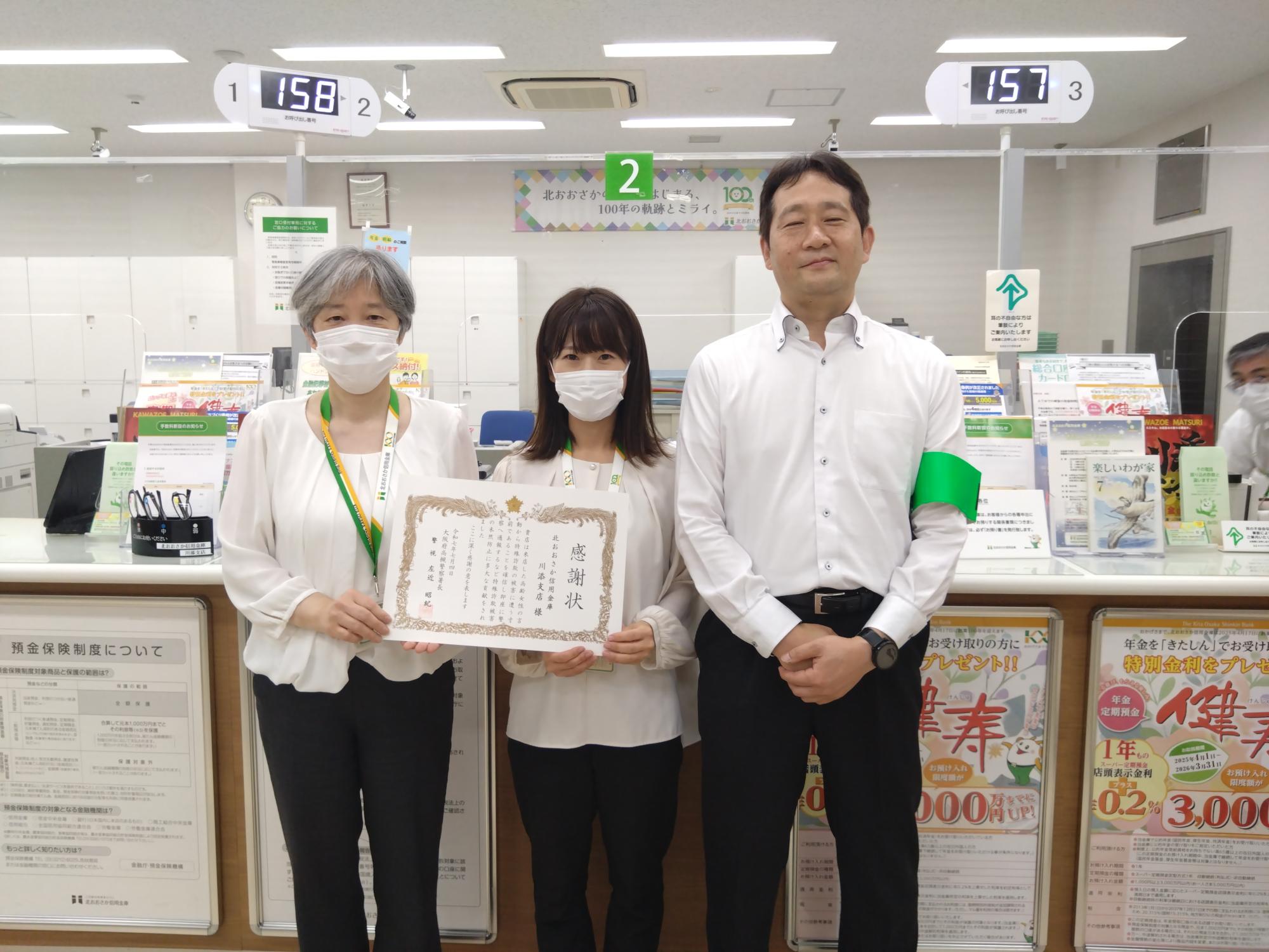 北おおさか信用金庫の女性行員2人が感謝状を手に持ち、男性と横一列に並んでる写真
