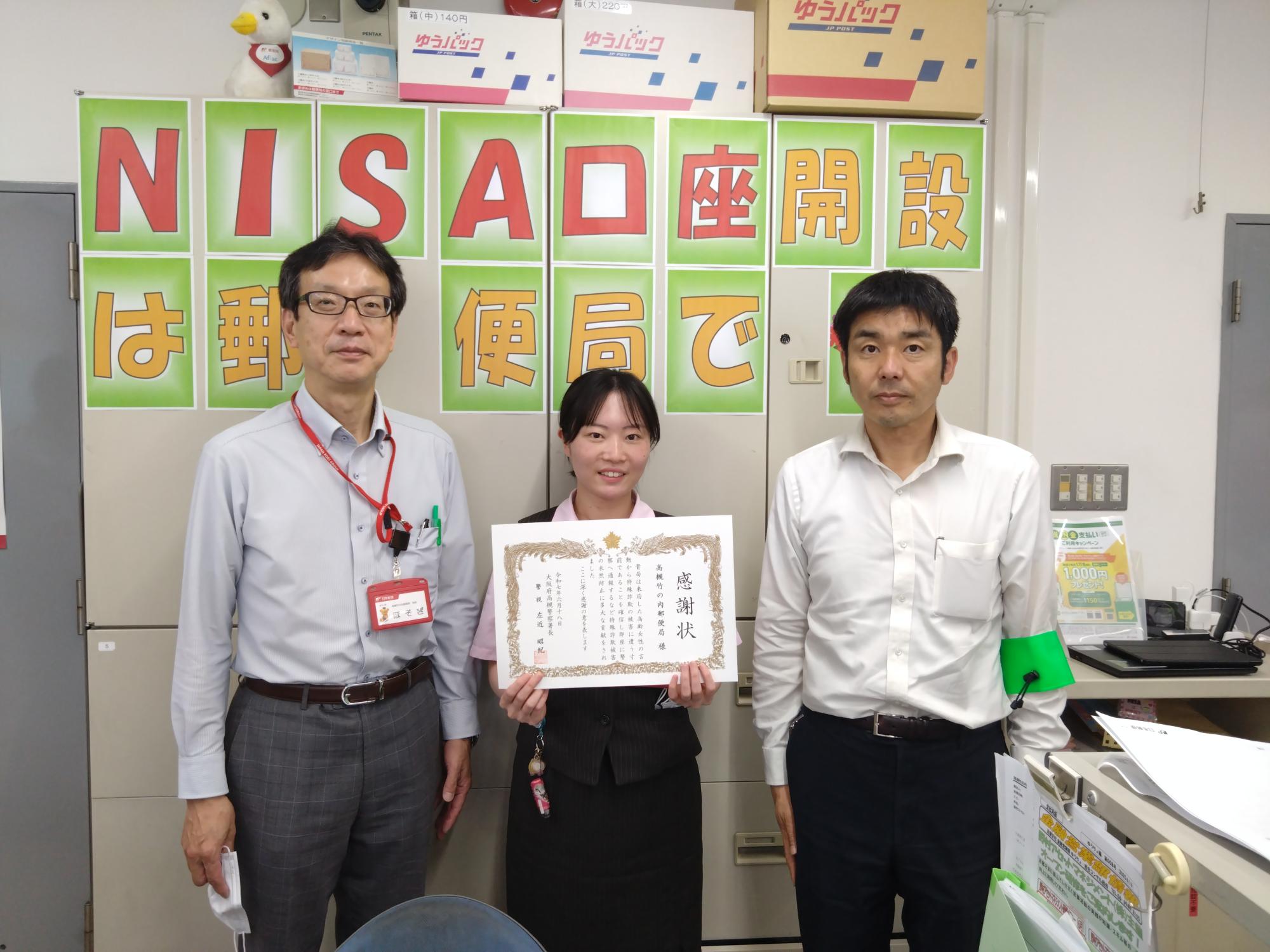 女性と1人の男性2人が横1列に並び、1人の女性が感謝状を持っている写真