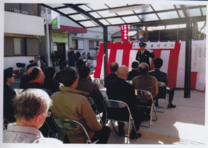 紅白幕の前で制服姿の警察官が挨拶をしている様子をパイプ椅子に座った方々が聞いている開所式の写真