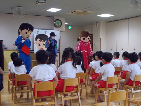 大阪府警察キャラクターゆうかいするぞうくん、れいちゃんと女性警察官が前に立ち、複数の園児が椅子に座り話を聞いてる写真