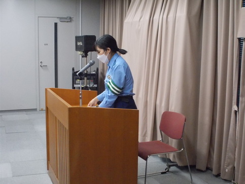 演題で資料を見ながら話をしている婦人警官を横から写した写真