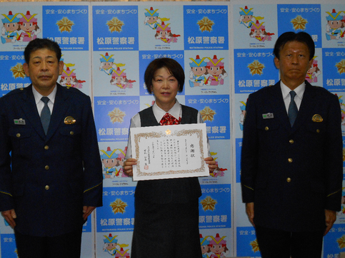 中央に感謝状を持った株式会社三菱UFJ銀行松原支店の職員の女性、その両端に警察署員が並んでいる記念写真