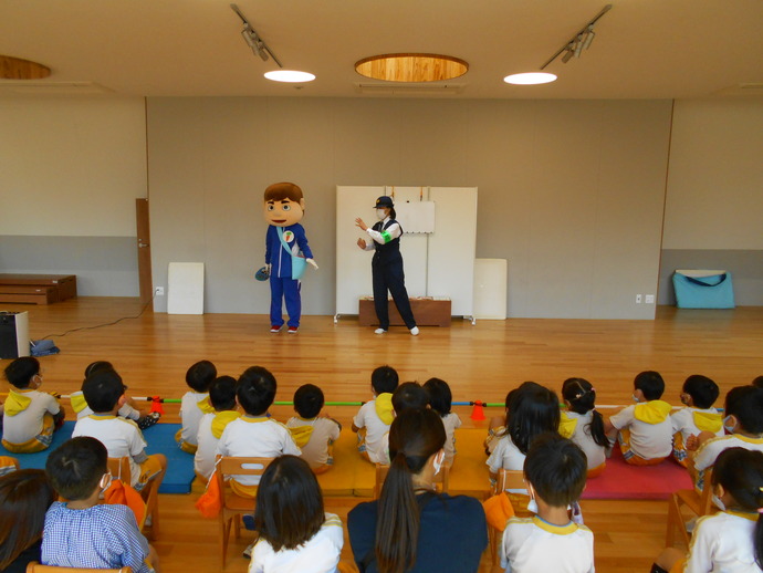 子どもたちの前で話をしている婦人警官と着ぐるみのゆうかいするぞうくん、床に座って話を聞いている子供たちの写真