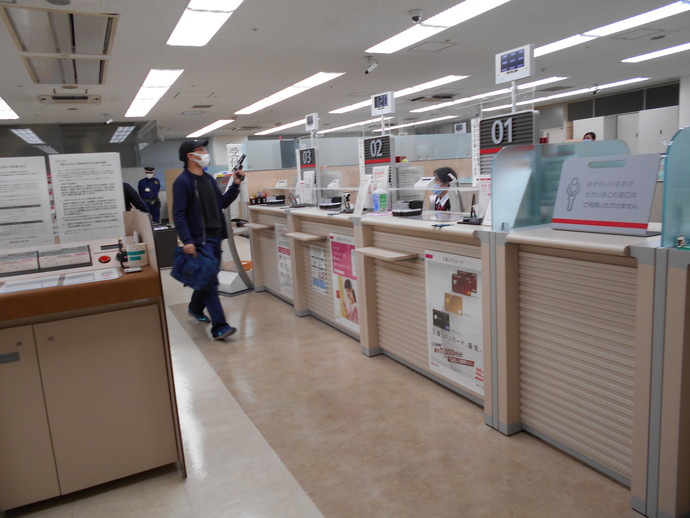 銀行の窓口に拳銃を右手に持った男性が近づいている訓練様子の写真