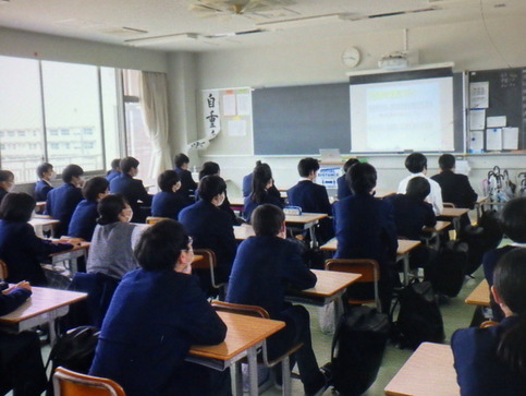 教室前方に置かれたスクリーンに映し出されたリモート画面を見る生徒たちの写真