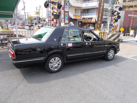 松原交通株式会社のタクシーの運転席の窓を開け運転手がポケットティッシュを持っている写真