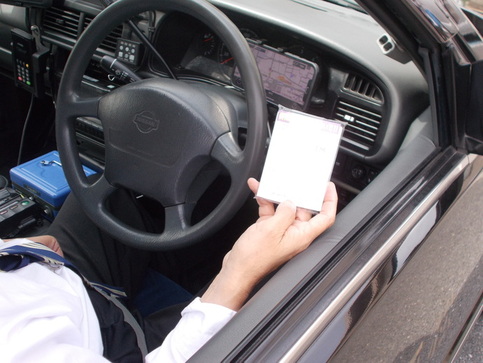 タクシーの運転手が窓を開け、ポケットティッシュを持った運転席をメインに写した写真