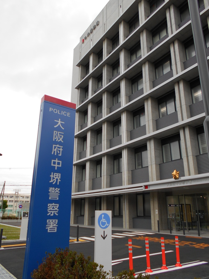 手前に看板が設置され、等間隔に窓があり7階建てでコンクリート造りになっている大阪府中堺警察署の外観写真