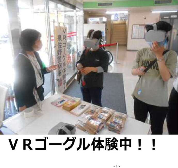 VRゴーグル体験中！！の文字と、VRゴーグルを付けた2名とスタッフが話している写真