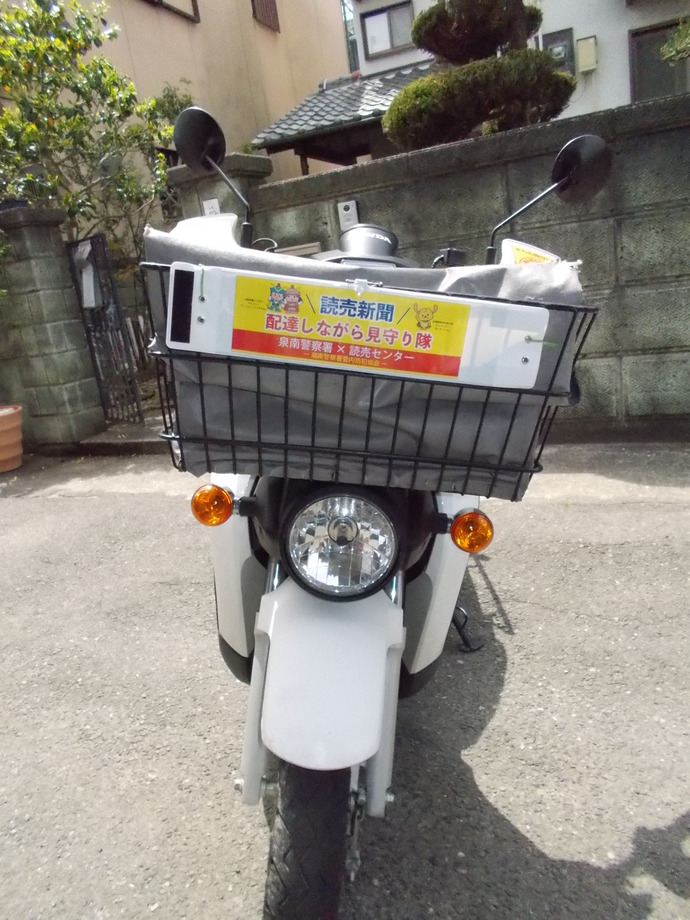 「配達しながら見守り隊」の腕章をつけたバイクの籠をアップで写した写真