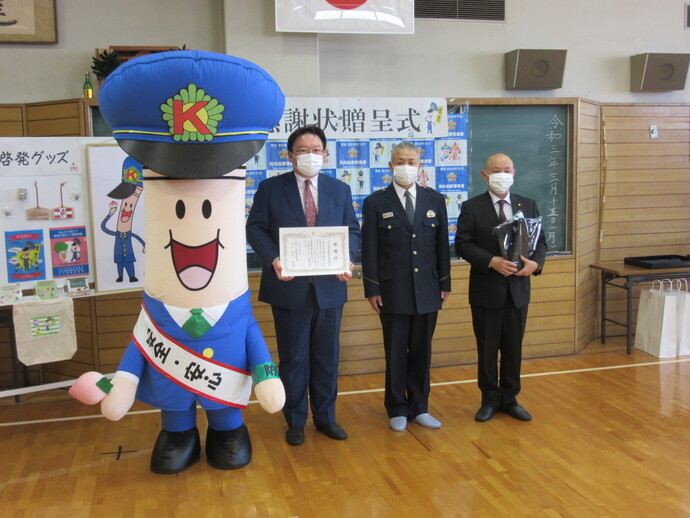 河内長野事業場防犯協会の2名の関係者が、ようじくんと河内長野警察署長一緒に並んで記念撮影をしている写真