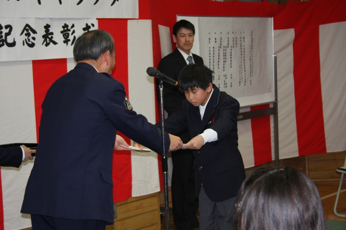 最優秀賞者の学生服姿の男の子が、河内長野警察署長から賞状が授与されている様子の写真
