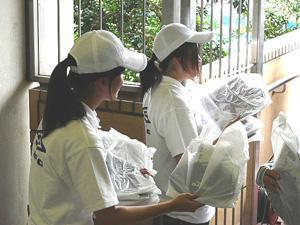 白いキャップと白いTシャツを着て安まちメール登録勧奨チラシを配布する二人の女声の写真