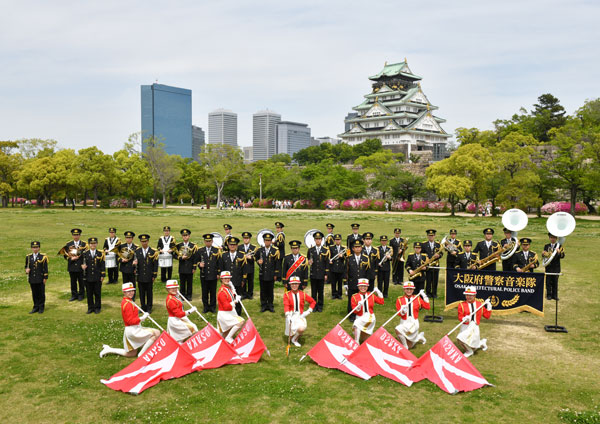 芝生の上、大阪城を背景にした大阪府警察音楽隊の集合写真