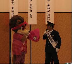 一日署長の森島寛晃氏がセレッソのマスコットとひったくり防止カバーの活用を呼びかけている様子