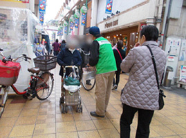 商店街の通行者に対し、自転車ヘルメット着用など、自転車のマナーについて安全指導を行っている様子