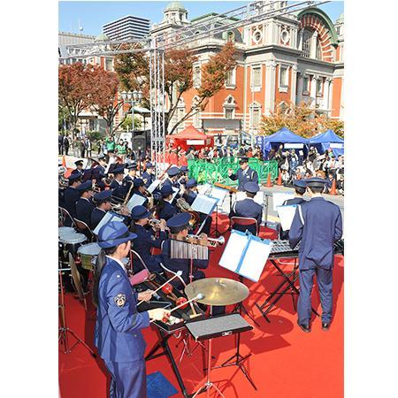 屋外の会場で演奏する警察音楽隊の写真