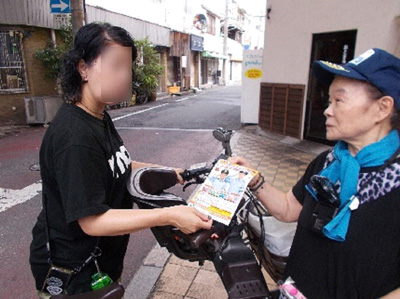 通行人に対し、秋の全国交通安全運動のリーフレットを配布し、交通安全を呼びかけている様子1