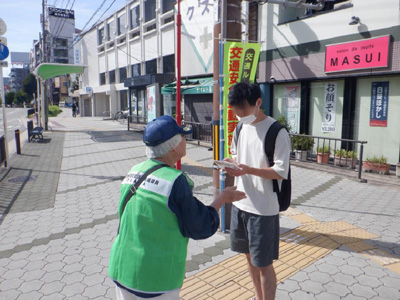 通行人に秋の全国交通安全運動のリーフレットを配布し、交通ルールの順守を呼びかけている様子
