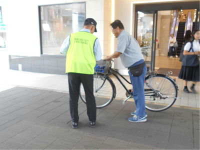 様々な世代の自転車利用者に、道路交通法の改正に関するチラシを配布し、交通ルール遵守とヘルメット着用を呼びかけている様子