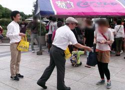 セレッソのテントの前で、スタジアムを訪れた女性に配布商品を手渡している様子