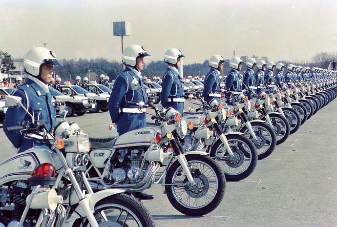 大阪万博会場で整列しているパトカーの前に白バイとヘルメットを被った警察官がズラリと整列している様子のカラー写真