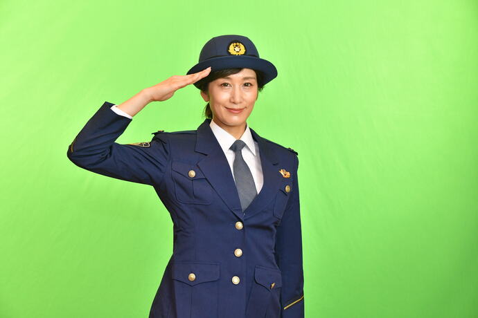 警察官の制服を着用し、片手を上げ敬礼のポーズをしているMBSアナウンサー西村麻子さんの写真