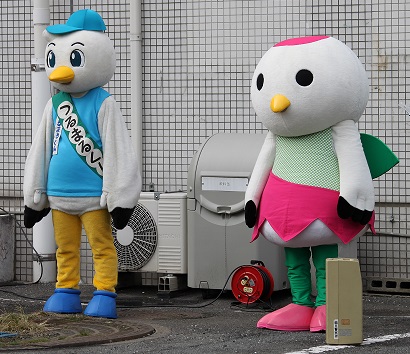 水色の帽子と服を着た鶴見防犯協会のキャラクター「つるまるくん」とチューリップを着ている、大阪市鶴見区のキャラクターつるりっぷの写真