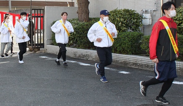 黄色のタスキをした、ランニングパトロール隊及び青色防犯パトロール隊が出発し、走り出している写真