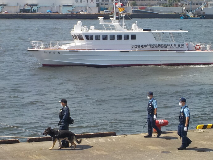 警棒をもった警察官2名と警備犬を連れている警察官1名が天保山岸壁付近を歩いており、海上には「テロ警戒中」と書かれてた警備艇が巡回している様子の写真