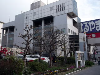 街路樹や花壇、掲示板が設置されている先に大正警察署が建っている外観写真