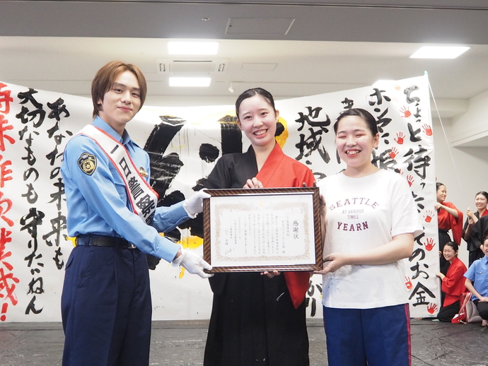 上宮高校書道パフォーマンス部の2人と山下幸輝さんが感謝状を3人で持っている写真