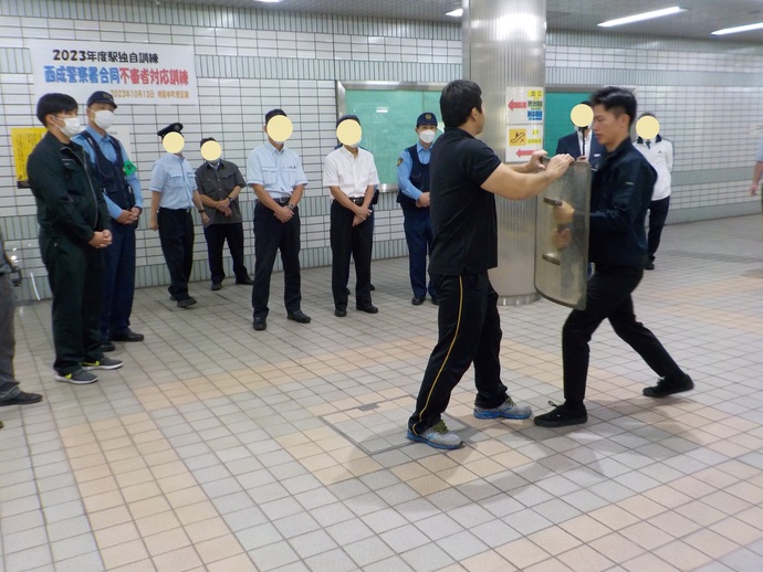 駅のホームにて、訓練に参加した駅員らが見守るなか、中央に立つ2名の男性が護身術の訓練をしている様子の写真