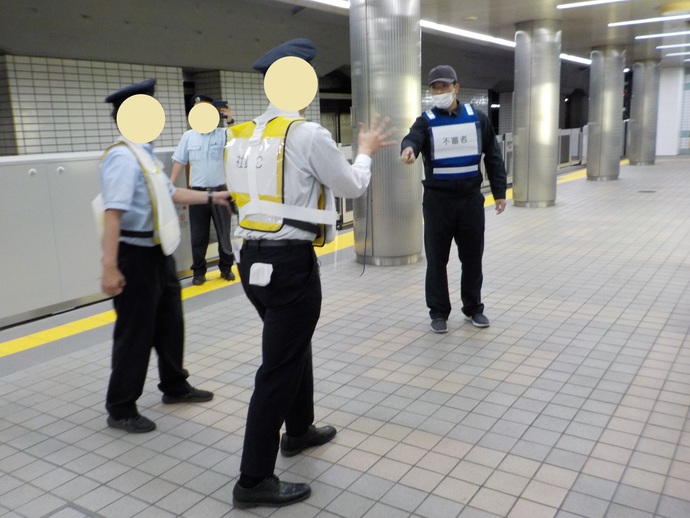 ナイフのようなものを持った不審者役と駅員が向かい合っており、駅員が不審者役に歩み寄っている様子の写真