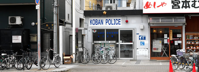 通り沿いに自転車が多く並び、飲食店の隣に建っている太子交番の外観写真