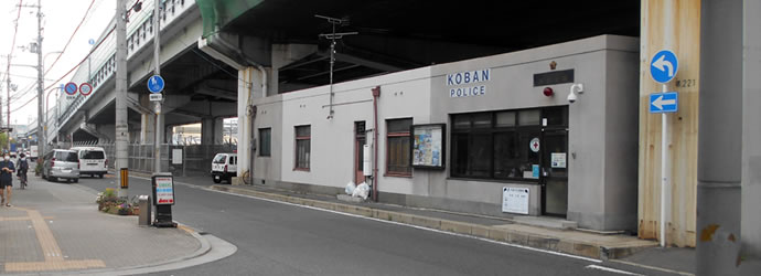 阪神高速道路の高架下に位置し、一方通行の標識が近くにある1階建てで正面右側に玄関があり千本交番の外観写真
