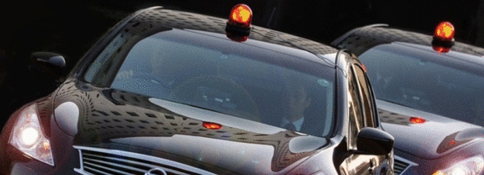 運転席と助手席に警察の方が乗り、赤色灯を付け出動している2台の黒い車の写真